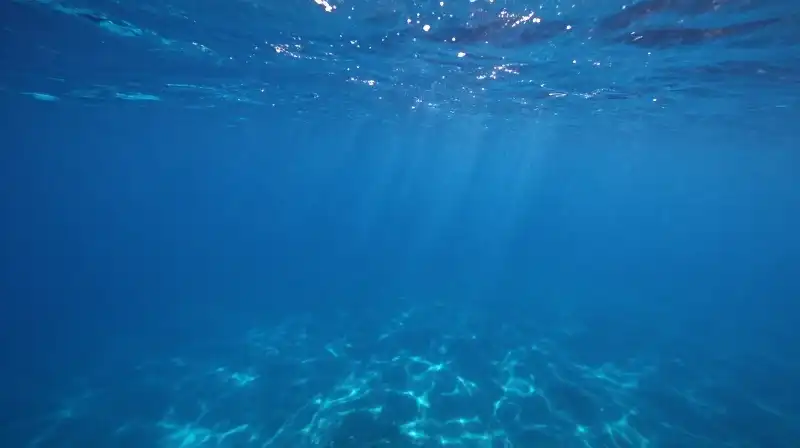 Sunlight pierces through a vast, deep blue ocean expanse