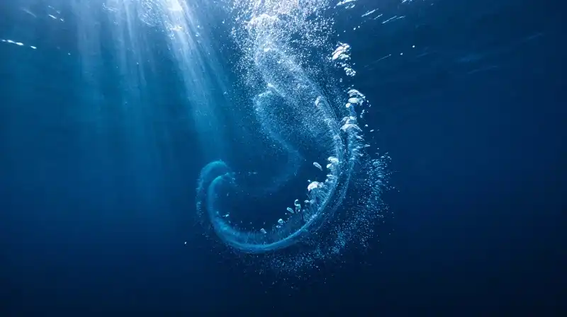 Swirling clouds of microscopic phytoplankton drift through deep blue water